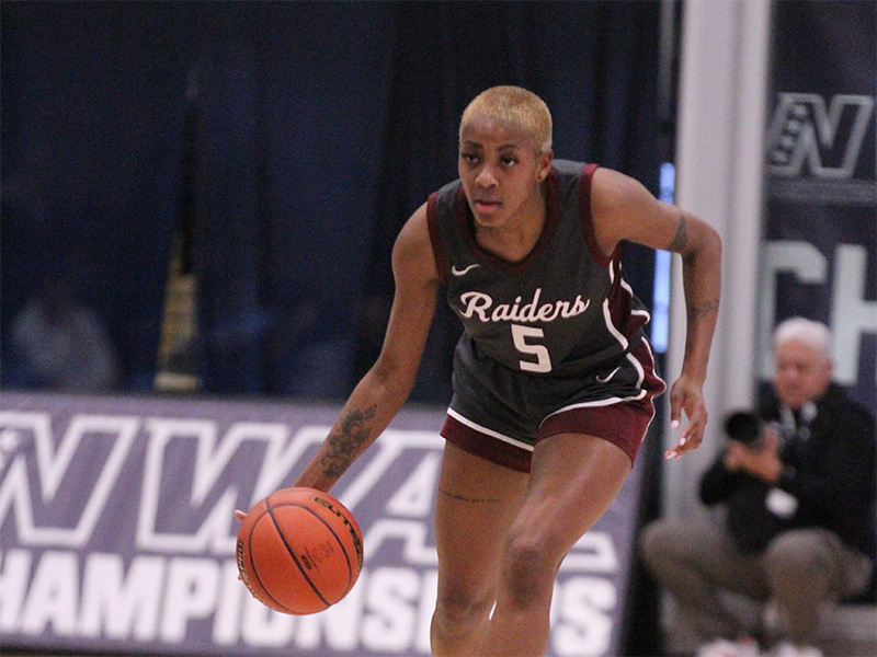basketball player dribbling in front of championship sign