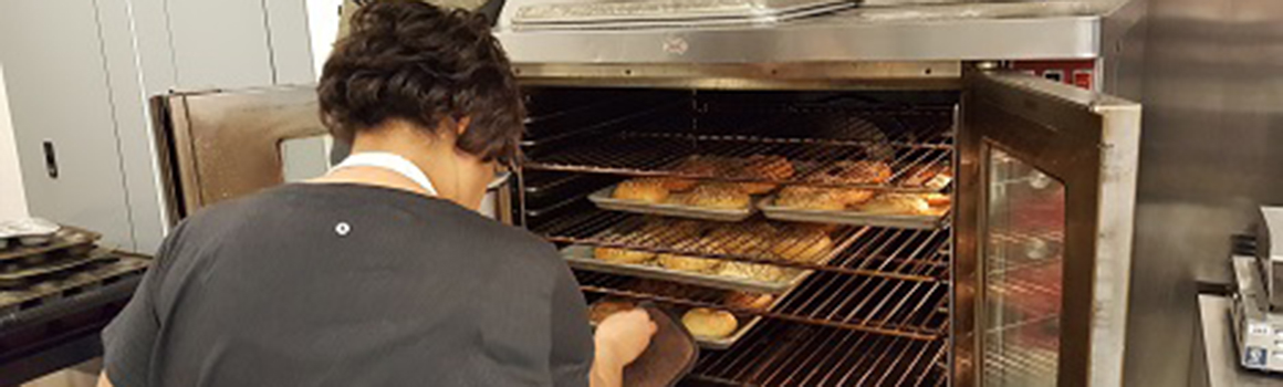 community and continuing education student taking bagels out of oven