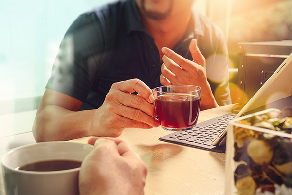 two people sitting at table with cups of tea