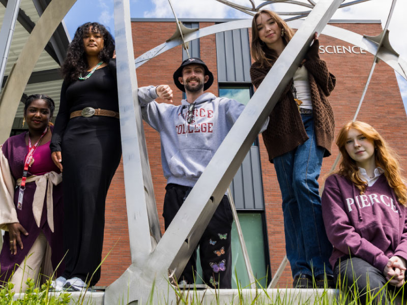 a group of students stands within a decorative metal sculpture