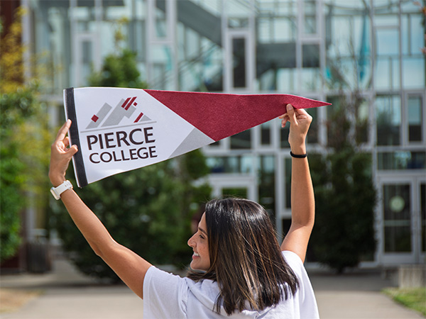 student with back to camera holding pierce college pennant
