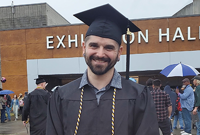 Jerad Lewis smiling in graduation cap and gown 