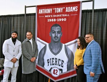 People stand next to large hall of fame banner for athlete