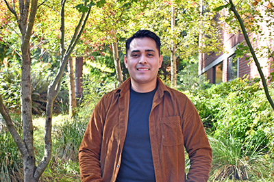 Vitaly Bravo Urrutia stands in front of greenery on the Pierce College Puyallup campus