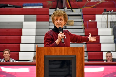 Dr. Michele L Johnson speaks from behind a podium in the newly dedicated gymnasium named in her honor