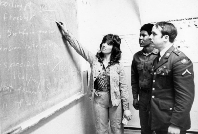 Students in uniform study in front of chalkboard in the 1970s