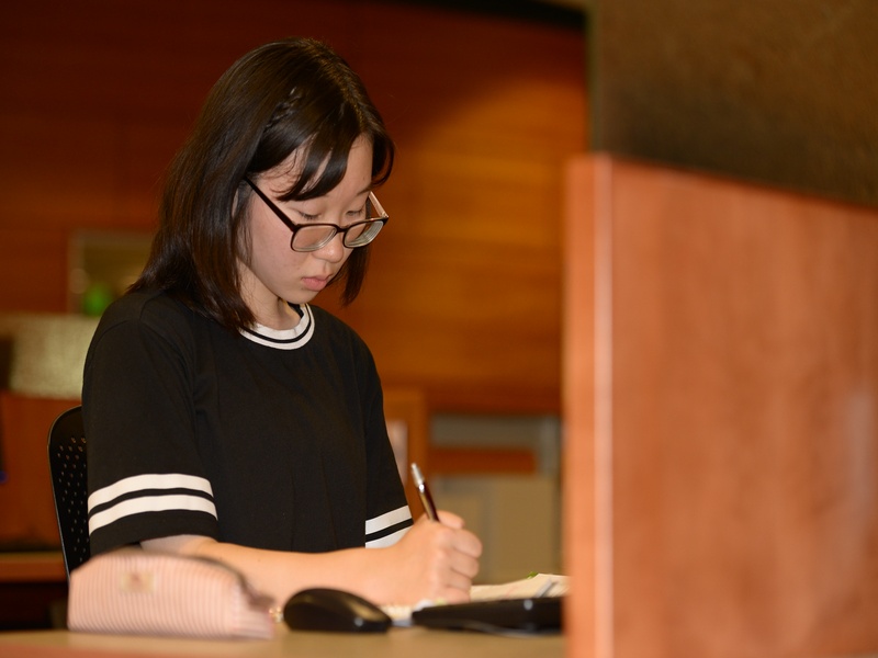 Person at a desk taking notes on a journal