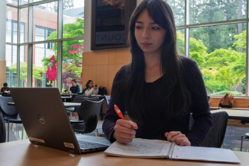 Student with laptop and notebook studying at table