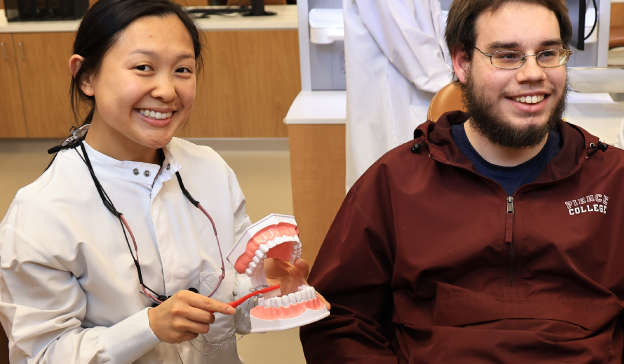 dental hygiene student demonstrating proper brushing techniques as part of patient education and preventative care training.