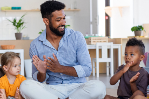 Man clapping while surrounded by happy children