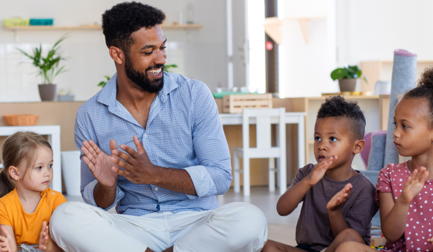 Man clapping while surrounded by happy children