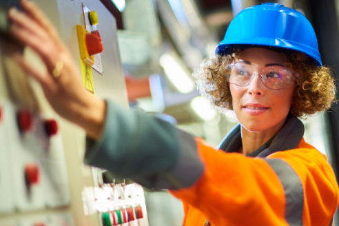 engineer in hard hat and protective clothing adjusting control panel