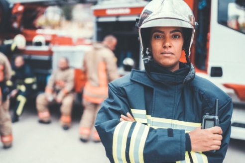 woman in protective fire gear in front of emergency vehicles