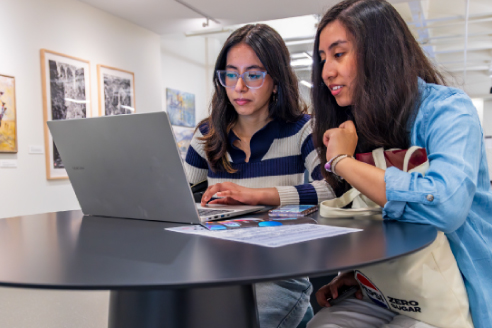 students working together on laptop in art gallery