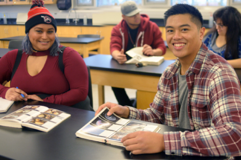 smiling students with textbooks in classroom