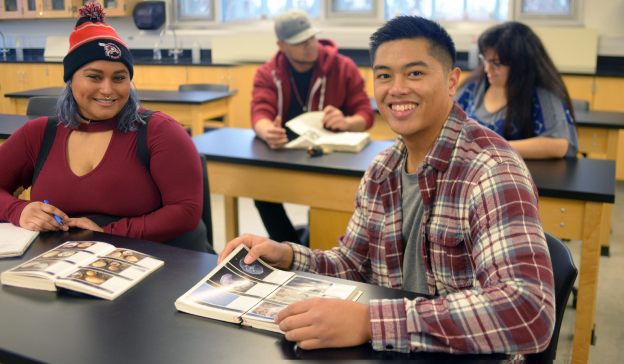 smiling students with textbooks in classroom