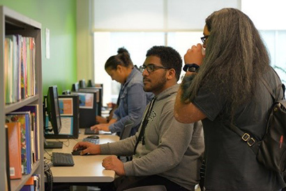 One student watching another student use a computer