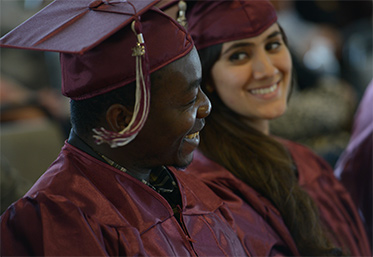 students in graduation caps and gowns smiling