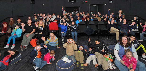 group of adults and children sitting in planetarium