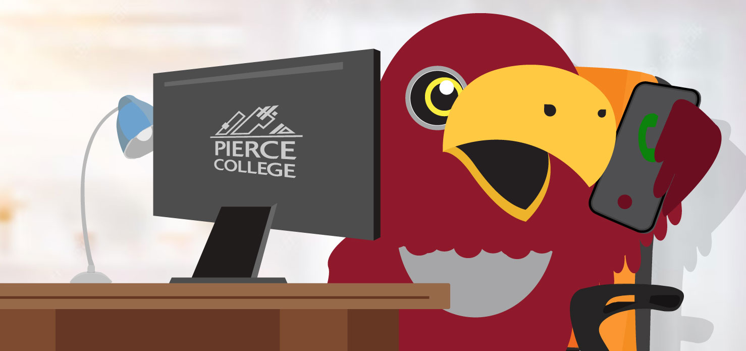 raider bird mascot sitting at desk with computer and mobile phone