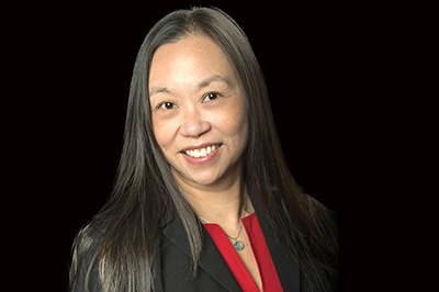 Ha Nguyen, Pierce College District's new VP of equity, engagement and belonging, pictured in front of trees on the Puyallup campus