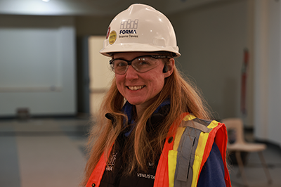 Brianna Davies, Pierce College Alumna, stands inside the Olympic South Building constructions site wearing hard hat and visibility vest
