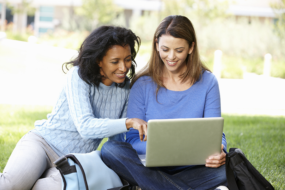 two people smiling and looking at a laptop