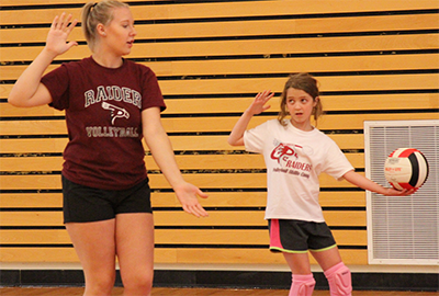 Raider athlete and camper playing volleyball