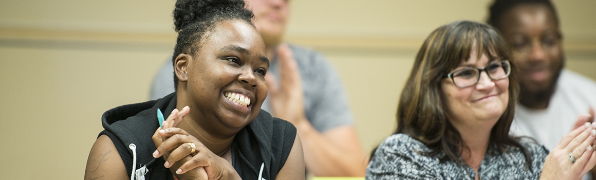 students in a classroom, smiling and clapping