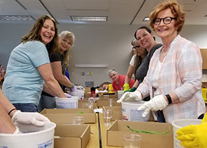 students in cce class at table with gloved hands in buckets