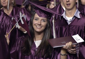 student in graduation attire holding diploma