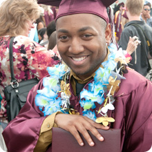 student in graduation gown and cap holding diploma