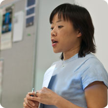 vision, mission, and outcomes instructor speaking in front of classroom while holding a paper and pen