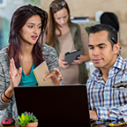 two people having a discussion while looking at a laptop screen two people having a discussion while looking at a laptop screen
