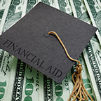 graduation cap that says financial aid resting on cash money