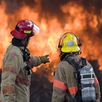 Two firefighters staring at flames